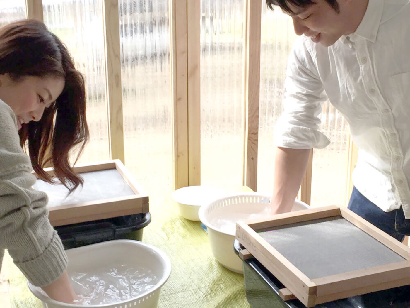陽の差す工房で紙を漉く2人